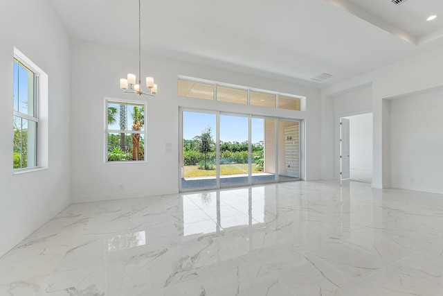 spare room featuring a chandelier, marble finish floor, a high ceiling, and baseboards