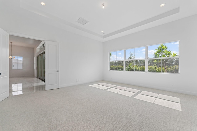 unfurnished bedroom featuring recessed lighting, light carpet, a notable chandelier, visible vents, and a tray ceiling