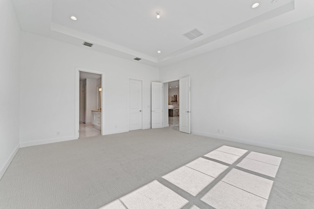 unfurnished bedroom with light carpet, visible vents, a raised ceiling, and recessed lighting