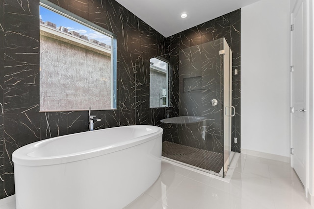 bathroom featuring plus walk in shower, tile patterned flooring, and tile walls