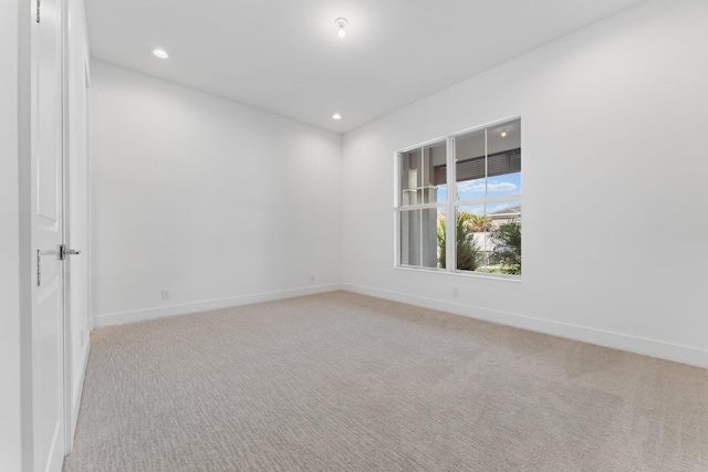 empty room with baseboards, recessed lighting, and light colored carpet