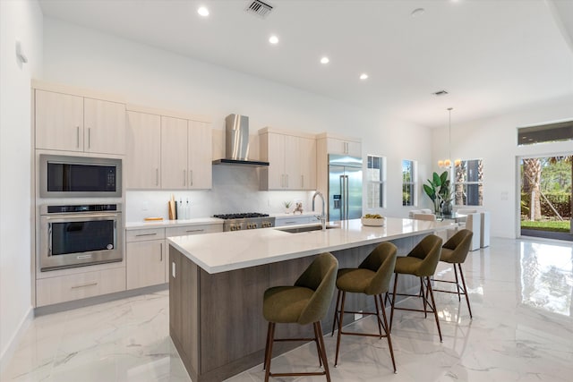 kitchen featuring visible vents, a sink, built in appliances, wall chimney exhaust hood, and marble finish floor