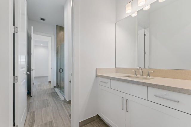 bathroom featuring tile patterned floors, a shower with door, and vanity