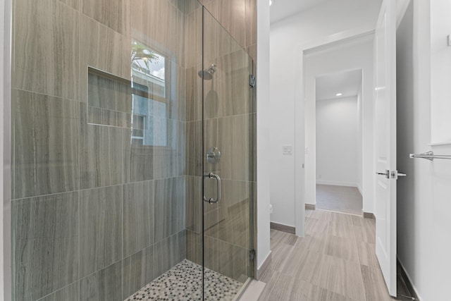 bathroom with a shower stall and baseboards