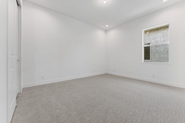 empty room featuring baseboards, light colored carpet, and recessed lighting