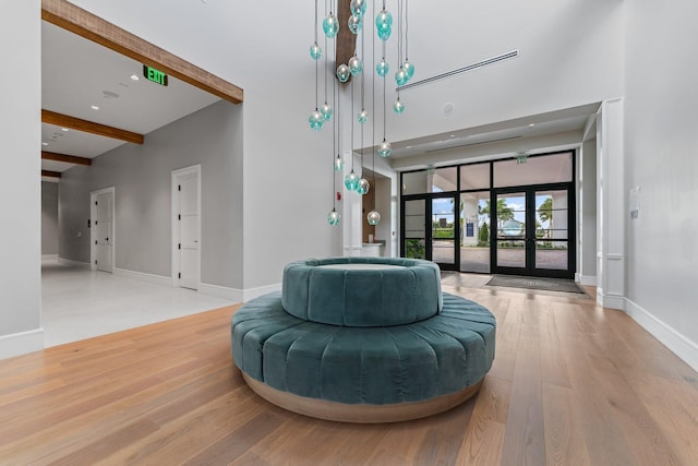 living area featuring beamed ceiling, french doors, and light hardwood / wood-style flooring