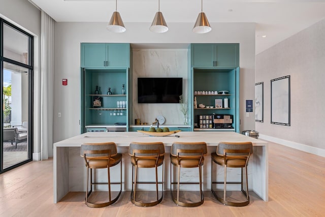 bar featuring baseboards, light wood-style floors, and pendant lighting