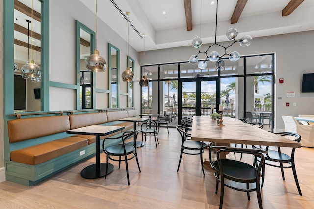 dining room with french doors, beamed ceiling, a towering ceiling, and light wood finished floors