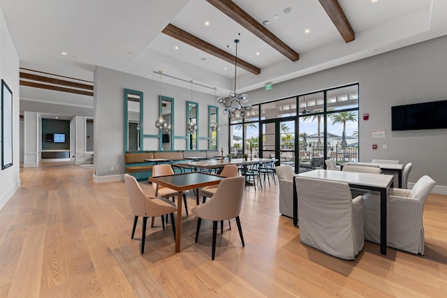 dining room with beamed ceiling, light hardwood / wood-style floors, a chandelier, and a high ceiling