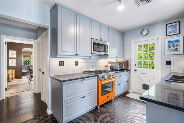 kitchen with dark tile flooring, backsplash, and range with gas cooktop