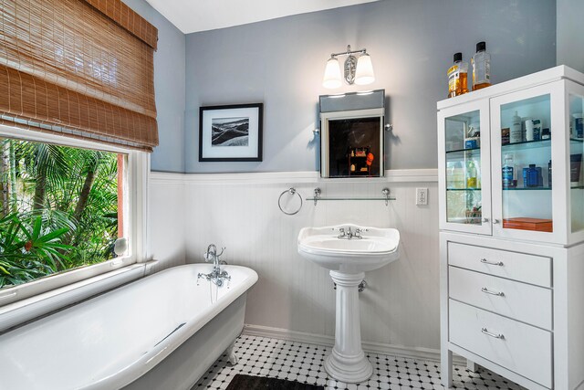 bathroom featuring a wealth of natural light, tile flooring, and a bath