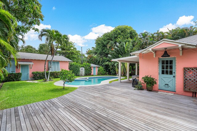 view of swimming pool featuring an outdoor structure, a lawn, and a wooden deck