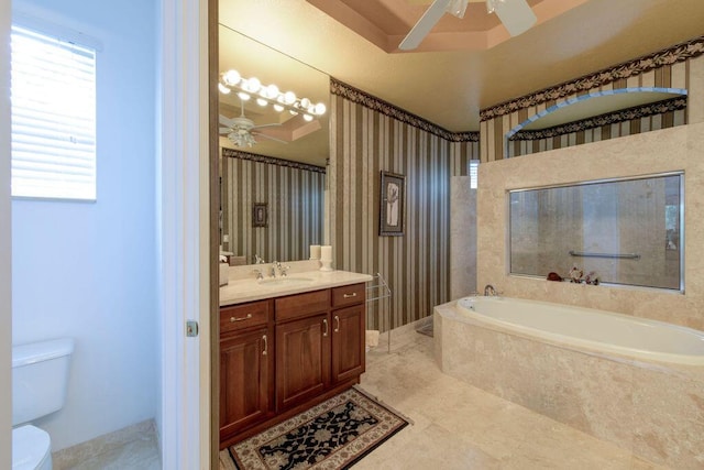 bathroom featuring toilet, ceiling fan, tiled tub, and vanity