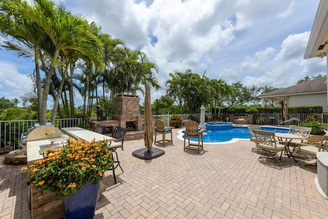 view of pool with area for grilling, a patio, an in ground hot tub, and an outdoor stone fireplace