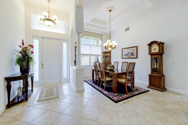 foyer featuring a high ceiling, light tile patterned floors, a chandelier, and ornate columns