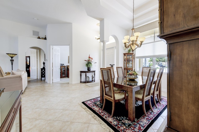 dining room with ornate columns, a high ceiling, light tile patterned flooring, and a notable chandelier