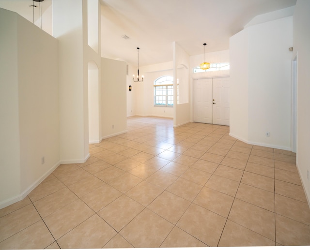 tiled spare room with a chandelier