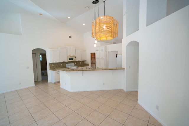 kitchen featuring stone counters, white cabinetry, high vaulted ceiling, white appliances, and light tile floors