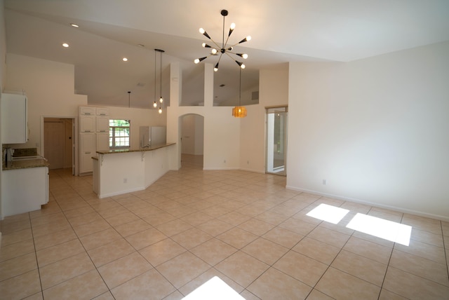 unfurnished living room featuring high vaulted ceiling, an inviting chandelier, and light tile floors