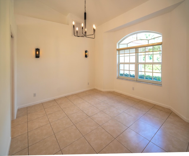 spare room with a healthy amount of sunlight, lofted ceiling, a notable chandelier, and light tile floors