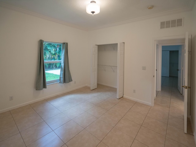 unfurnished bedroom featuring ornamental molding, light tile flooring, and a closet