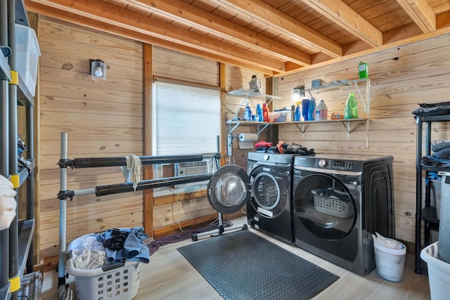 washroom with washing machine and dryer, light wood-type flooring, wood ceiling, and wooden walls