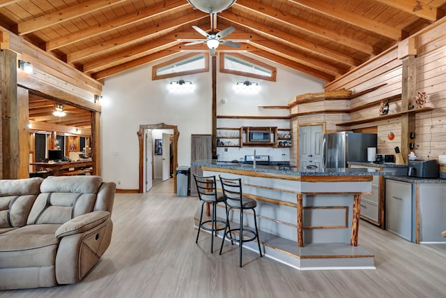 kitchen featuring wood ceiling, light hardwood / wood-style flooring, ceiling fan, high vaulted ceiling, and stainless steel appliances