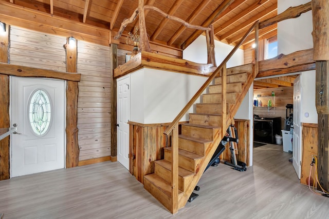 foyer with light wood-type flooring, lofted ceiling with beams, wooden ceiling, and wood walls