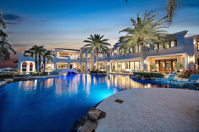 pool at dusk with french doors and a patio