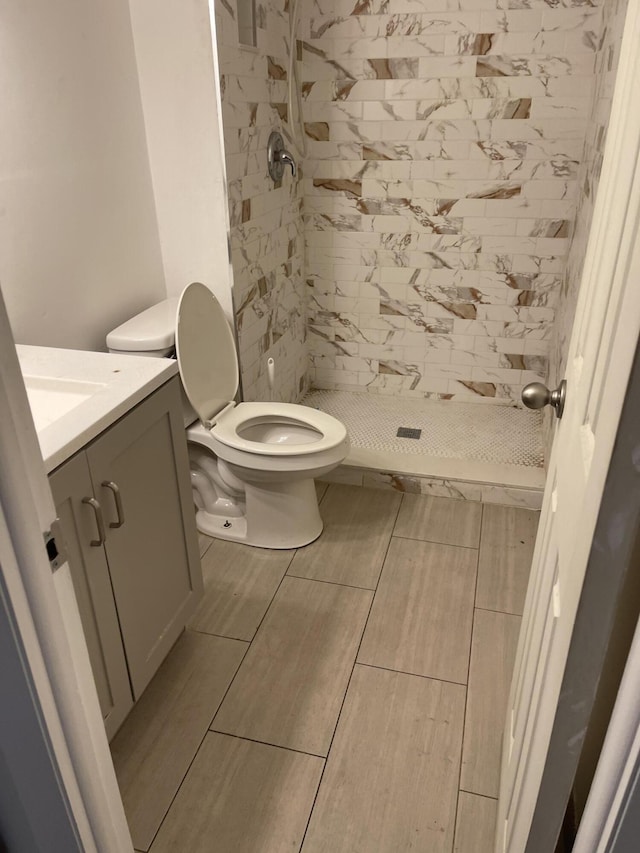 bathroom with tiled shower, vanity, and toilet