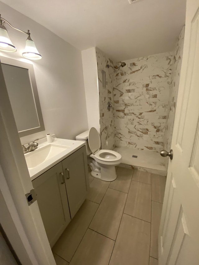 bathroom featuring tile patterned flooring, vanity, toilet, and walk in shower