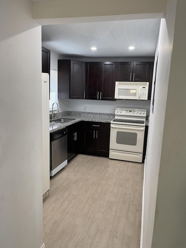 kitchen with light stone countertops, sink, white appliances, and light hardwood / wood-style flooring