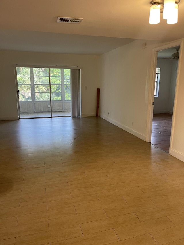 spare room with light hardwood / wood-style floors and a notable chandelier