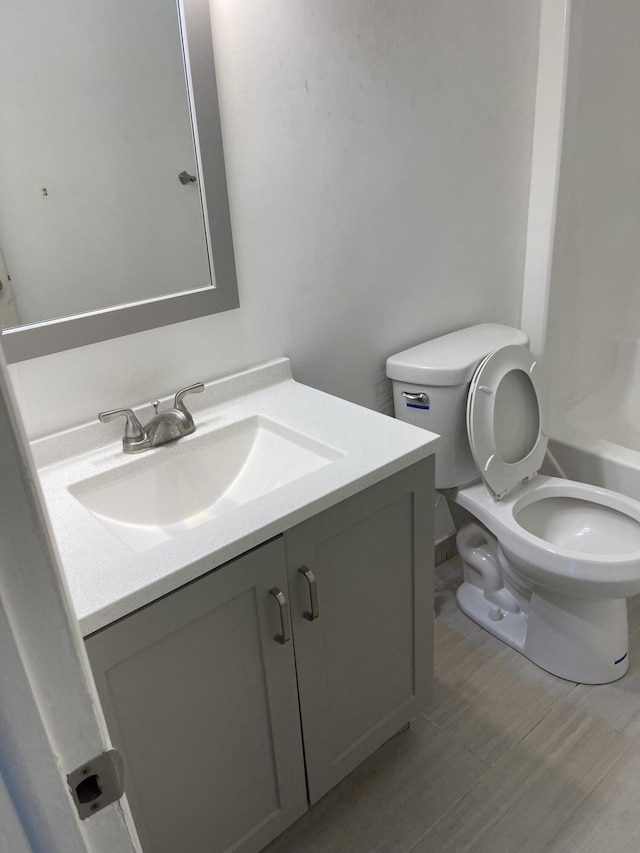 bathroom with hardwood / wood-style floors, vanity, and toilet