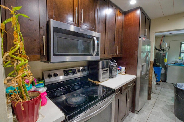 kitchen with electric water heater, stainless steel appliances, and light tile patterned flooring