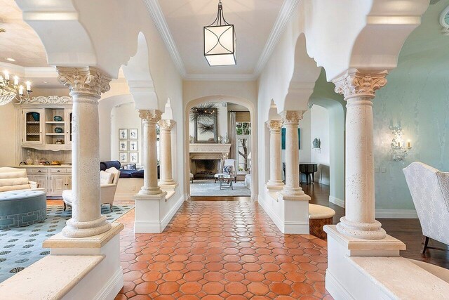 foyer entrance featuring ornamental molding, a fireplace, decorative columns, and tile patterned flooring