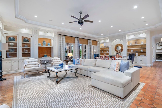 tiled living room with built in shelves, ornamental molding, a fireplace, and ceiling fan