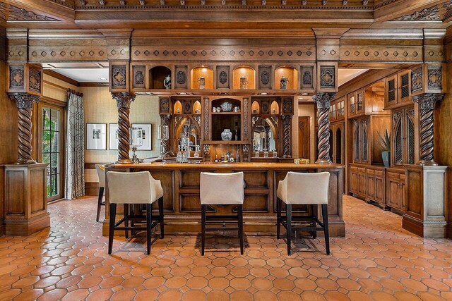 kitchen featuring ornamental molding, light tile patterned flooring, and a kitchen bar