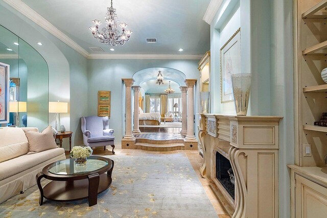 tiled living room featuring built in features, crown molding, decorative columns, and an inviting chandelier