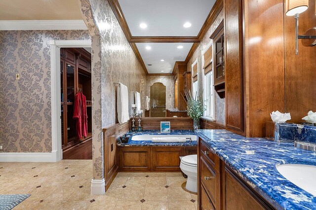 bathroom with tile patterned flooring, crown molding, a bathing tub, toilet, and vanity