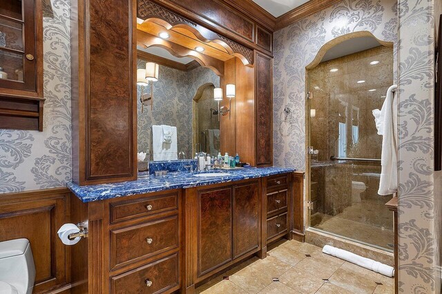 bathroom with a shower with door, tile patterned flooring, toilet, vanity, and ornamental molding