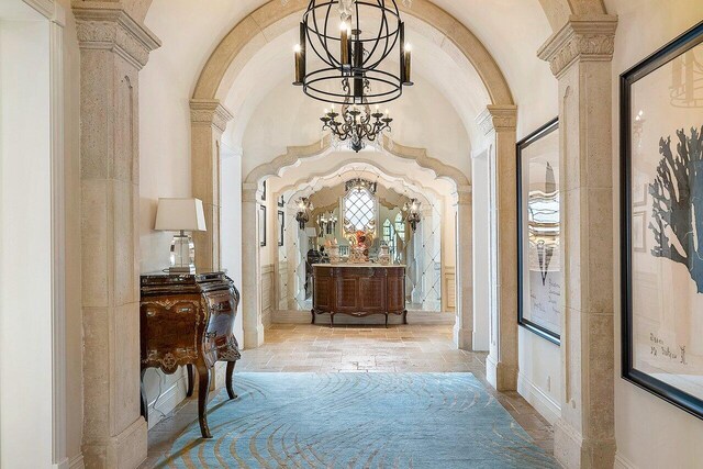 hall featuring a chandelier, light tile patterned flooring, and decorative columns