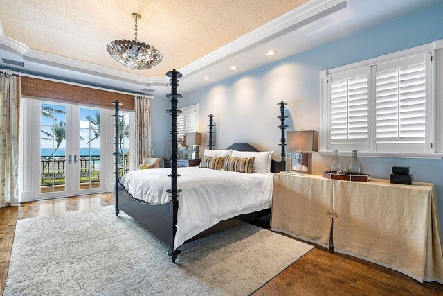 bedroom with hardwood / wood-style flooring, a tray ceiling, crown molding, french doors, and access to outside