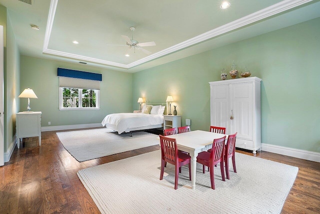 bedroom with ceiling fan, a tray ceiling, and hardwood / wood-style flooring