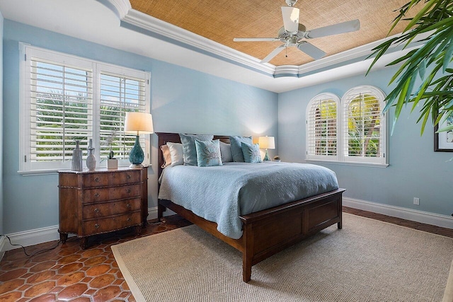 bedroom with multiple windows, ceiling fan, and a tray ceiling