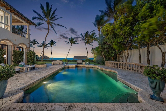 pool at dusk featuring a patio