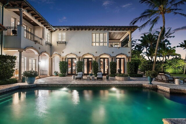 pool at dusk featuring a patio