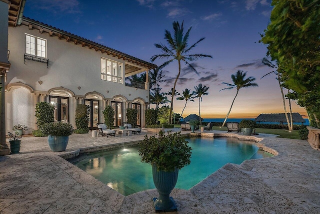 pool at dusk featuring a patio