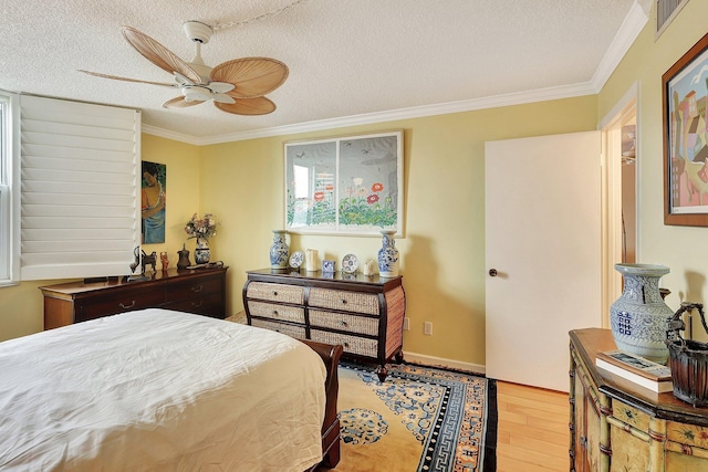 bedroom with light wood-type flooring, a textured ceiling, ceiling fan, and crown molding