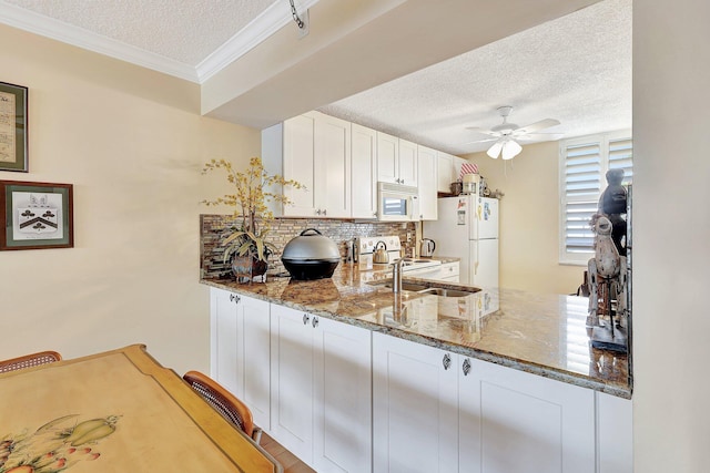 kitchen featuring white cabinets, white appliances, a textured ceiling, and stone counters